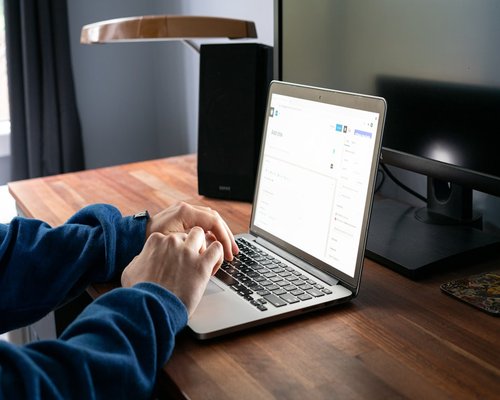 Woman adjusting laptop angle on a clean wooden desk